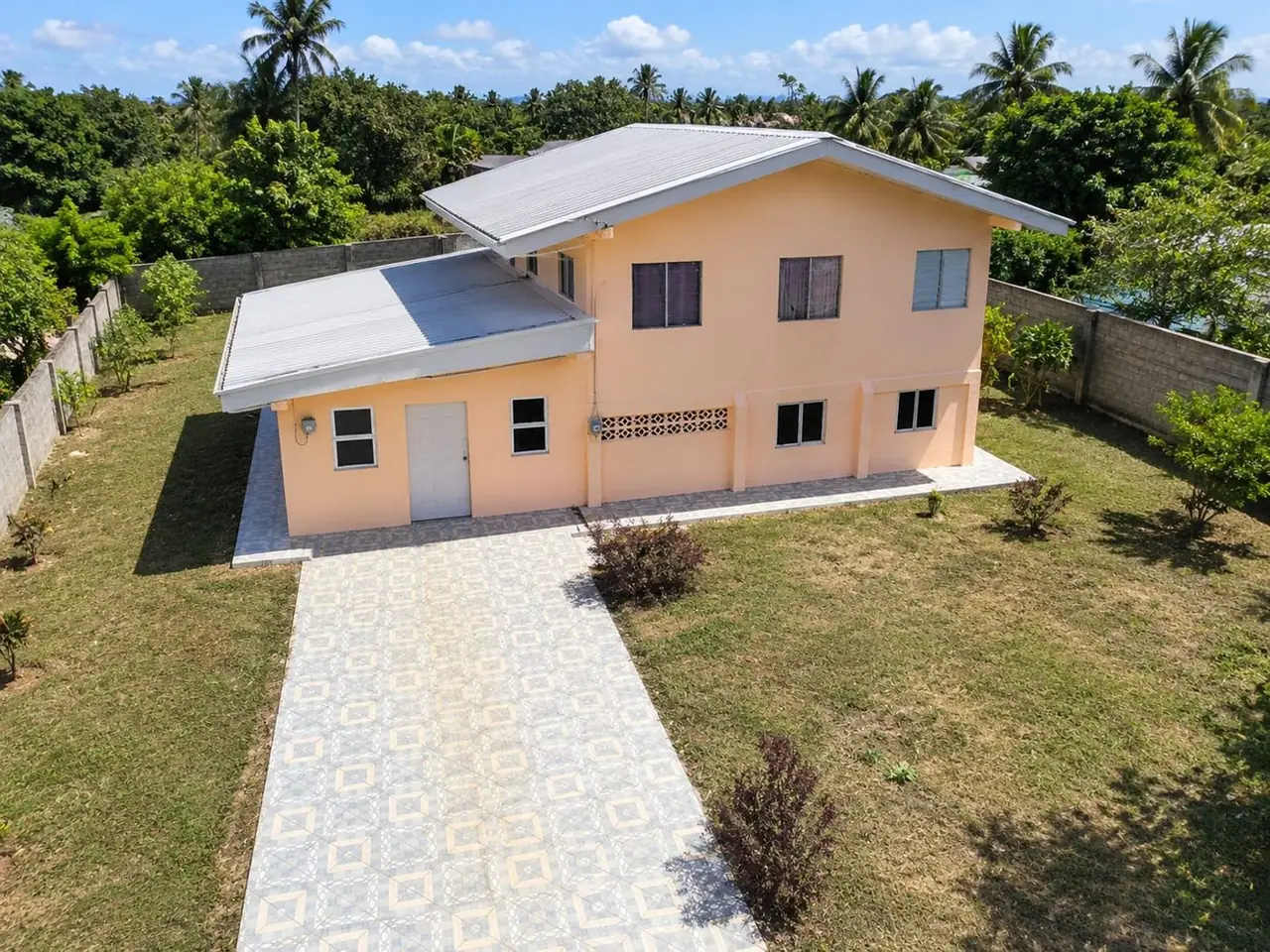 Aerial view of the two-storey peach house, tiled driveway and walled yard