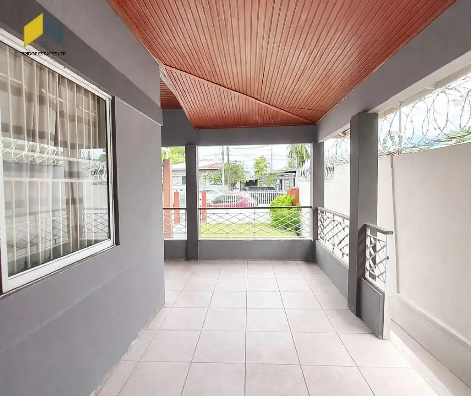 Covered front porch with tiled floor and decorative iron grilles