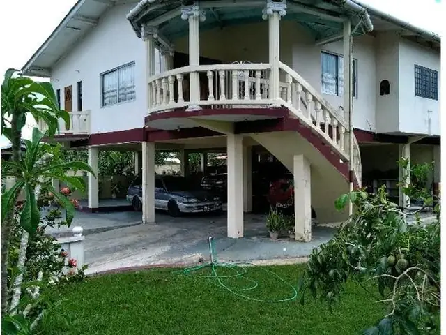 Front of the two-storey home with curved balcony and garden