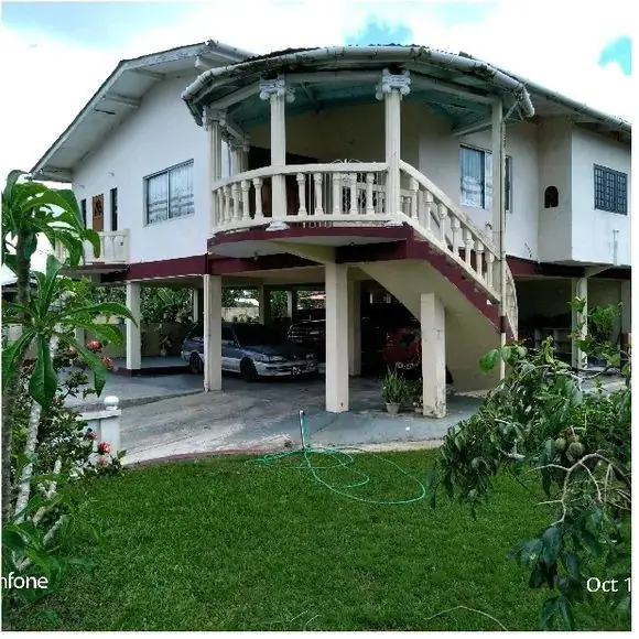 Front of the two-storey home with curved balcony and garden